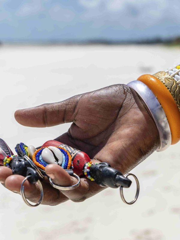 Masai tribal female hand with a colorful bracelet holds souvenirs for sale for tourists on the island of Zanzibar, Tanzania, East Africa. Travel and vacation concept SSUCv3H4sIAAAAAAAACoxSTU/jMBC9I/EfIp9bUTeJk3LclbitxB1xmDhDY+HaUWyzqlD/O+MkXswCq73Z78178/l6fVUUrAOnJLstXuOP/krr4PwEXllD8G6z4hOaHqccwV55OynQOdiBl4OBExJogtYRvswkcx58cOiyZJ06Om/l8zhYbwkvs3AJHo/k/1GwVvuw/ItEzCQpiGL3aEeNbJMxLnSR+aWcRK3BoA2OJX7J943ZD4Tgzzd34IY4kC9Mf2rrB2WO737L4zGNBI5o5Dk2ccnam1AjLNN4WELZ82+P02ludw2C0Cubtf9iJWj316DGScmY/11GBc2rSjJpg/FTLIGlDpi2doSO5nRbPJEnJnwA5yi8T3i+EToMe8ryGOvnBlZX1tPK4peX+3LP27rl9U404lCKNWA5gUGRz1xOKjCM2kKPMemfHXw6Dl635FUJzpeQtLe4iJPy/r/kQtTVKv9wmhSo+n+dJivFvi2bqhHzolehijmp36Z84hy32JbVtkKJ20PVdNvdvhWHmkPb7mpSXd4AAAD//wMA3rTiOXIDAAA=